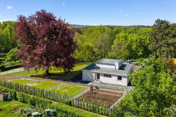 Luftaufnahme des Musterhaus „Am Horn“, umgeben von Garten und viel Grün