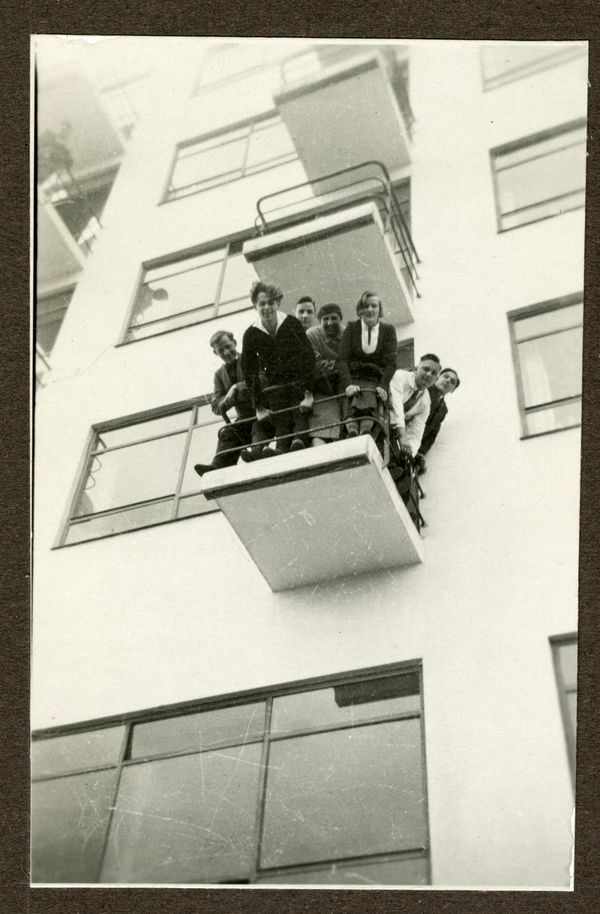 Schwarz-weiß-Bild einer Gruppe Menschen, die von einem Balkon nach unten blickt